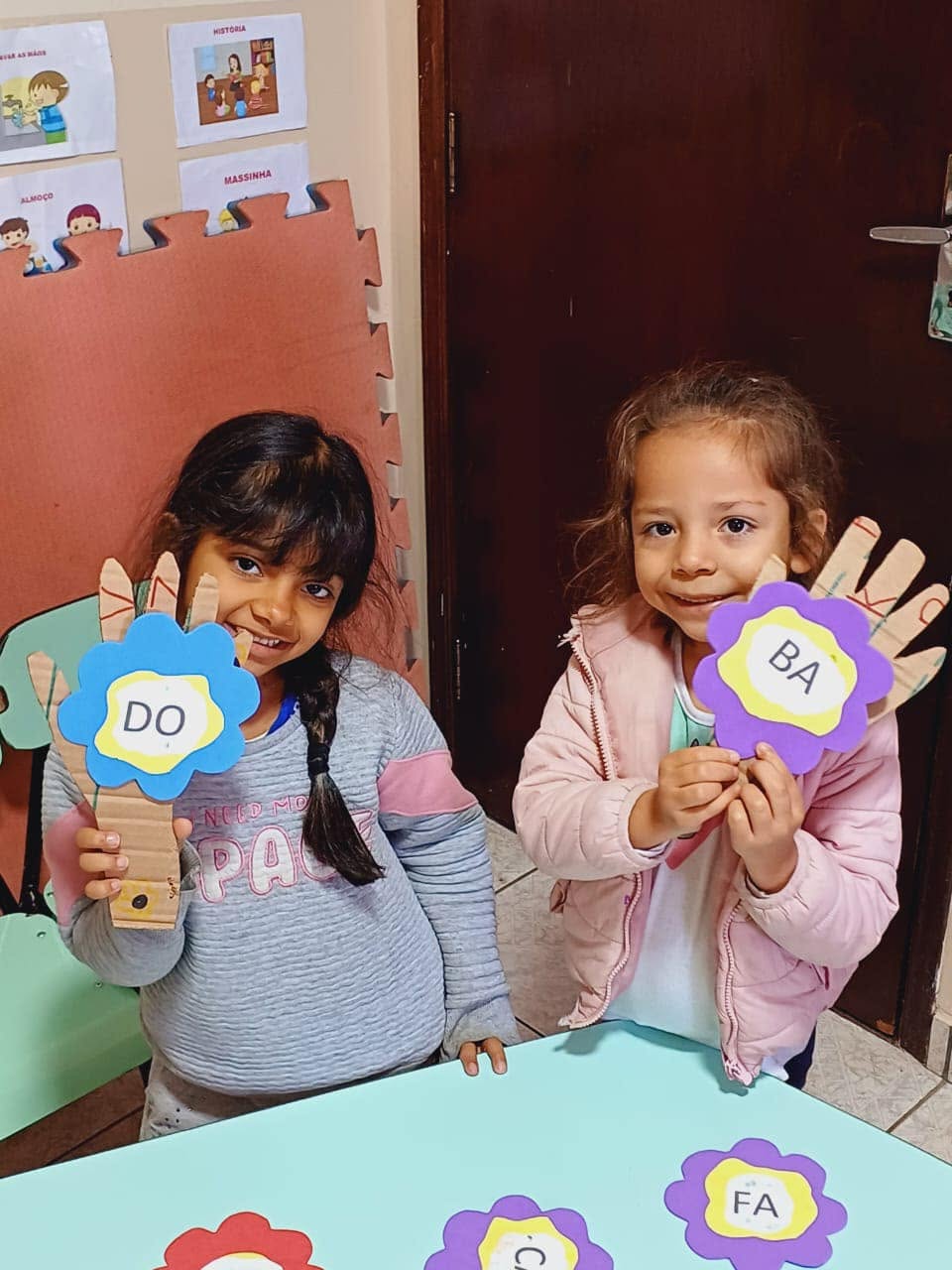 Duas meninas mostrando flores com sílabas